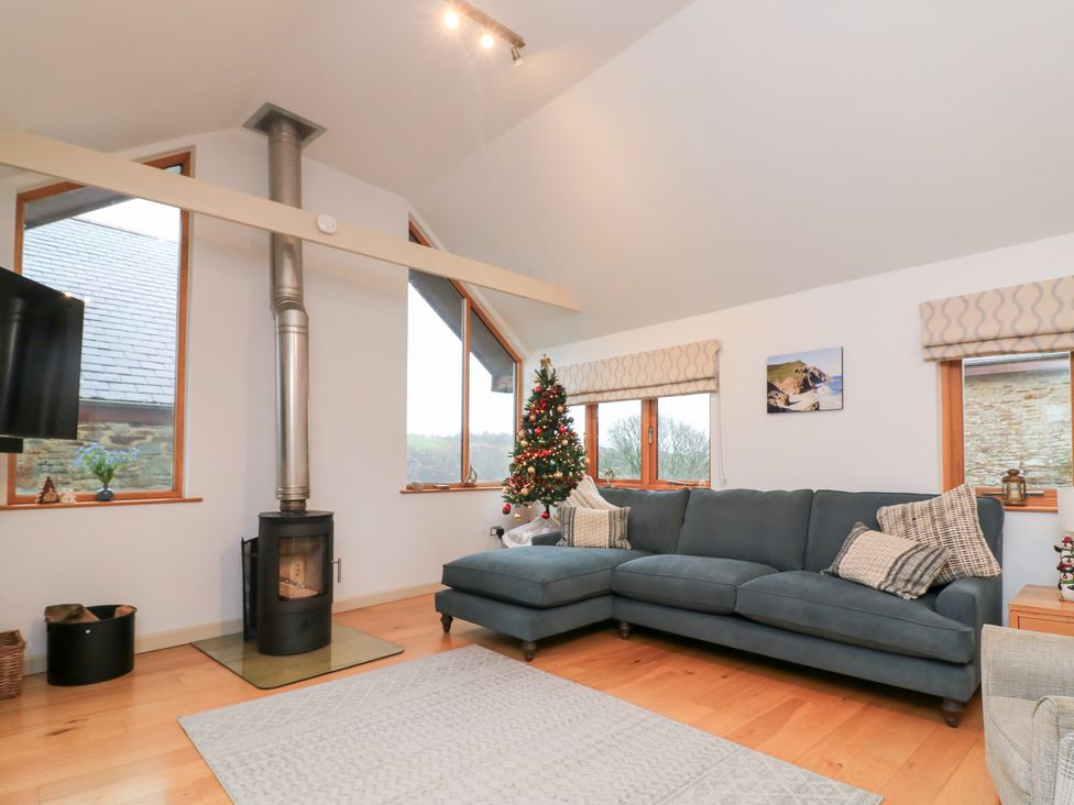 A living room with a corner sofa and a Christmas tree at Courtyard Cottage in Dartmouth