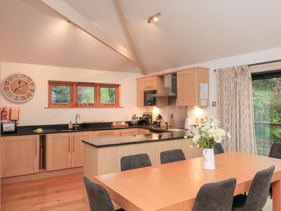 A kitchen with wooden cabinets and a dining table at Courtyard Cottage in Dartmouth