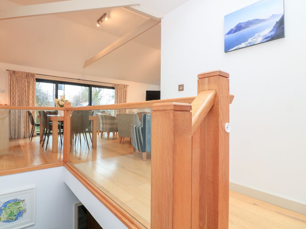 A living room with a railing and dining area at Courtyard Cottage in Dartmouth