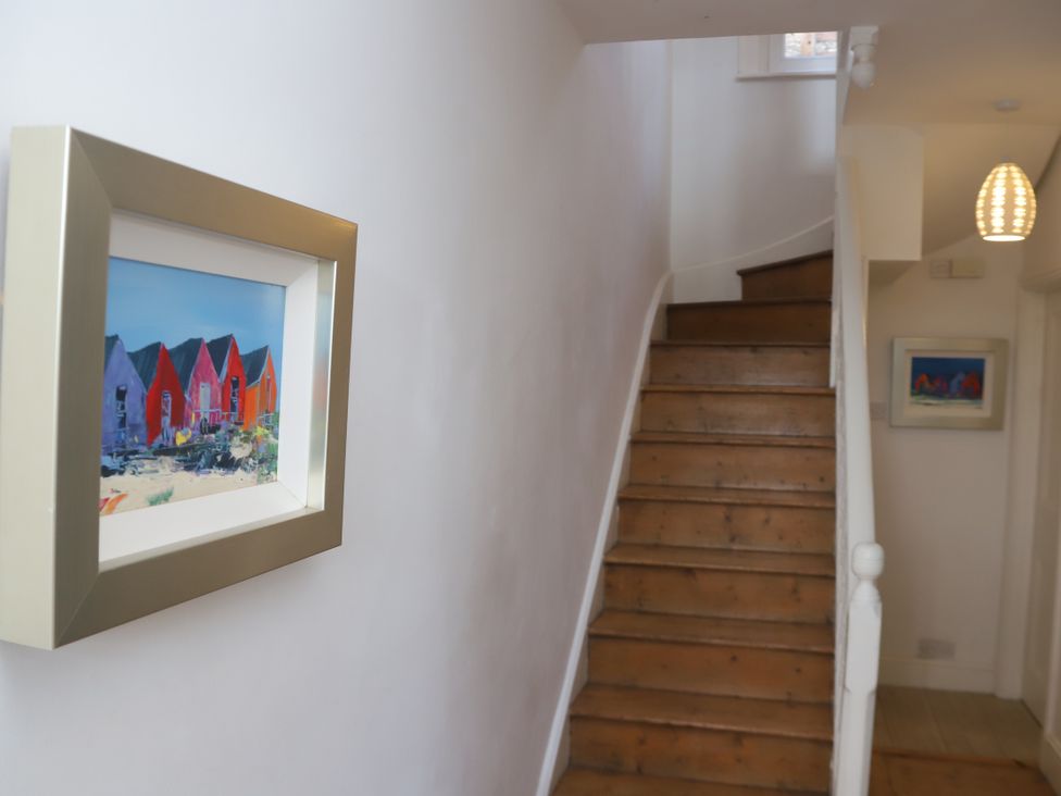 A hallway with a staircase and framed photos at Dart Views Dartmouth