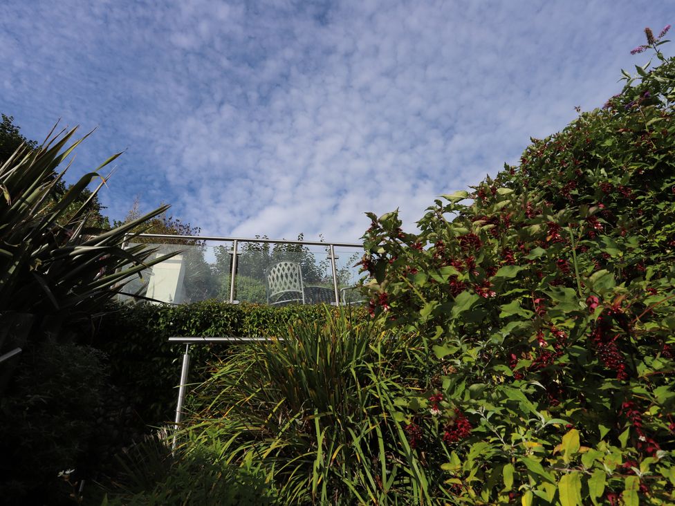 A garden with plants and a chair behind glass railing at Dart Views in Dartmouth