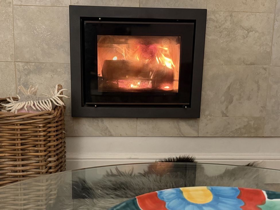 A fireplace with burning logs and a basket at Dart Views in Dartmouth