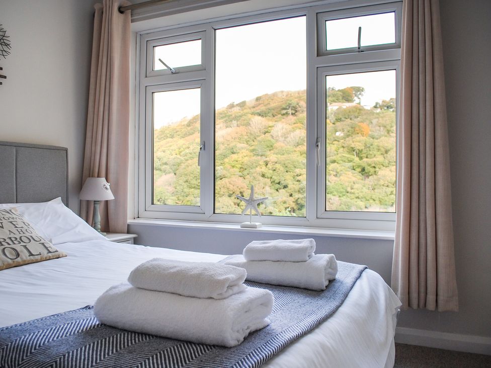 A bedroom with a bed and towels arranged at Dolphins in Salcombe