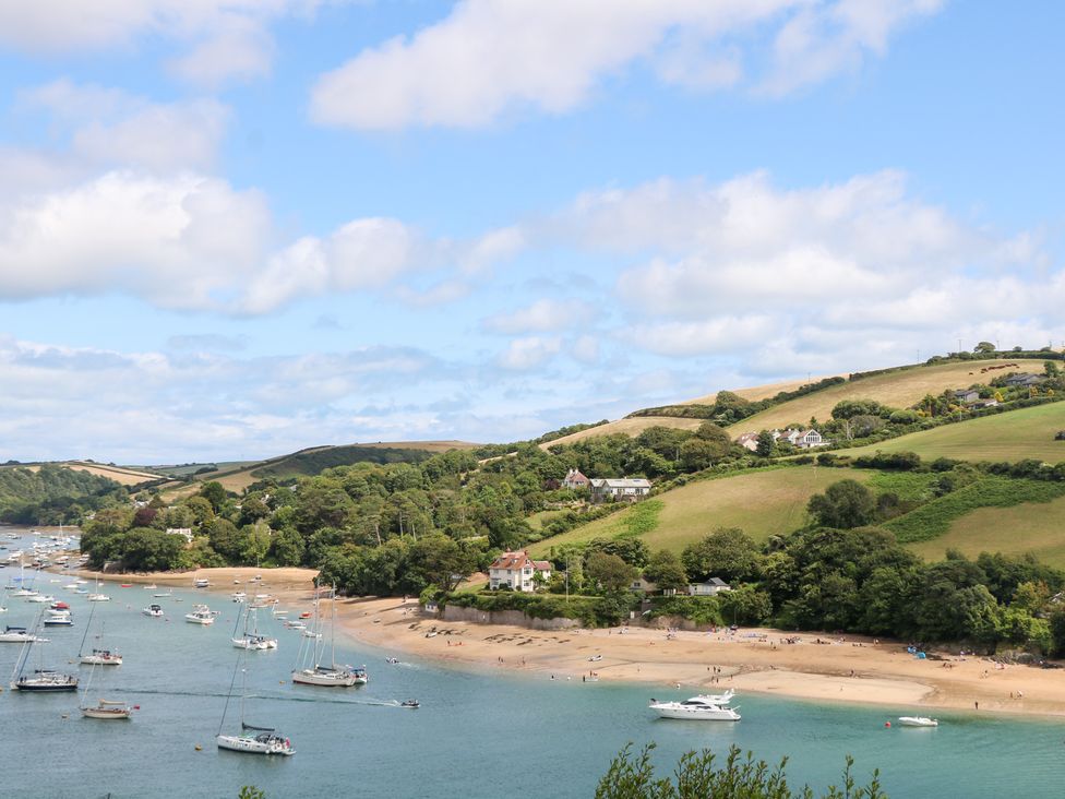 A beach with boats anchored and houses on the hillside at Edinburgh House in Salcombe