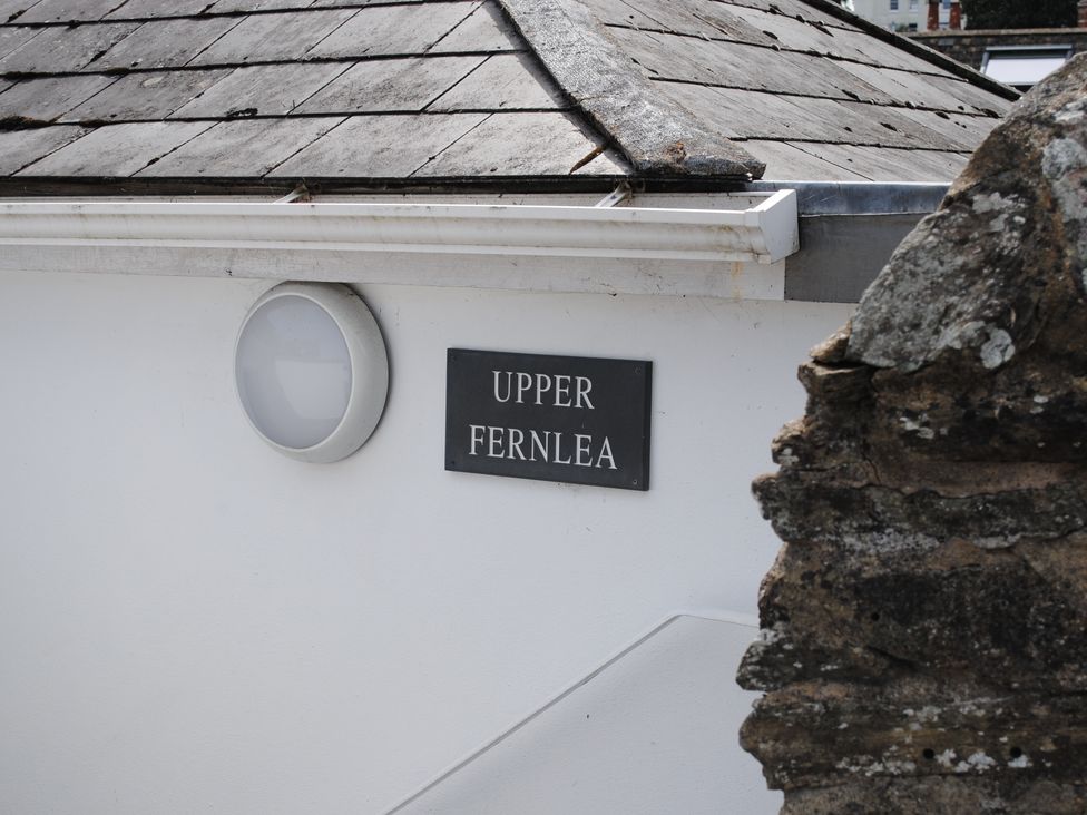 A sign for Upper Fernlea on a white building wall in Salcombe