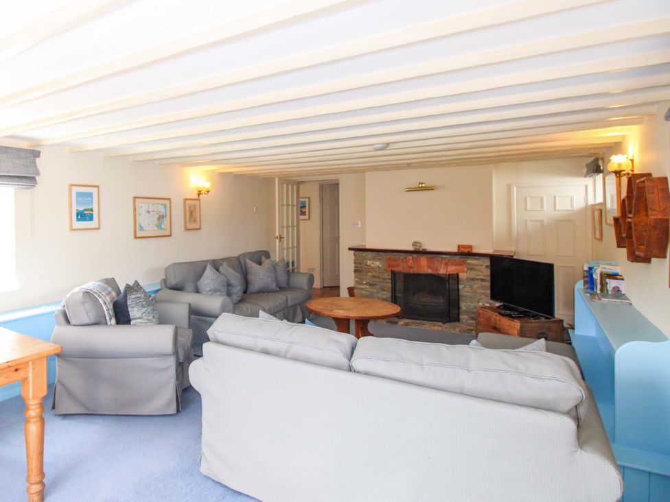 A living room with a fireplace and sofa at Orchard Barn in Salcombe