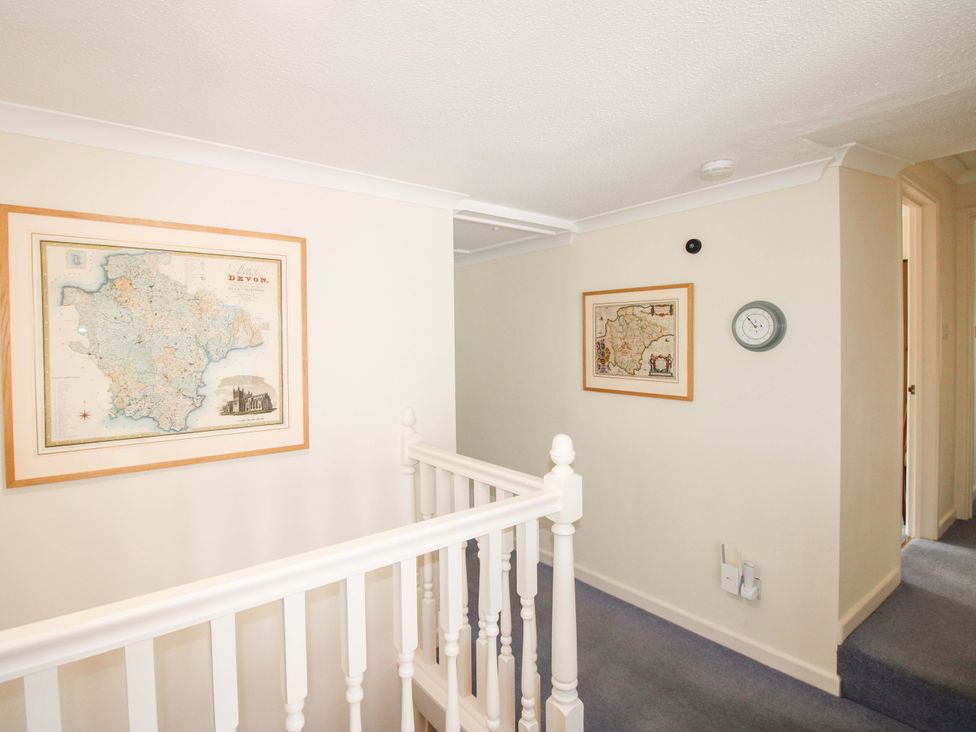 A hallway with maps on the wall and a clock at Orchard Barn Salcombe