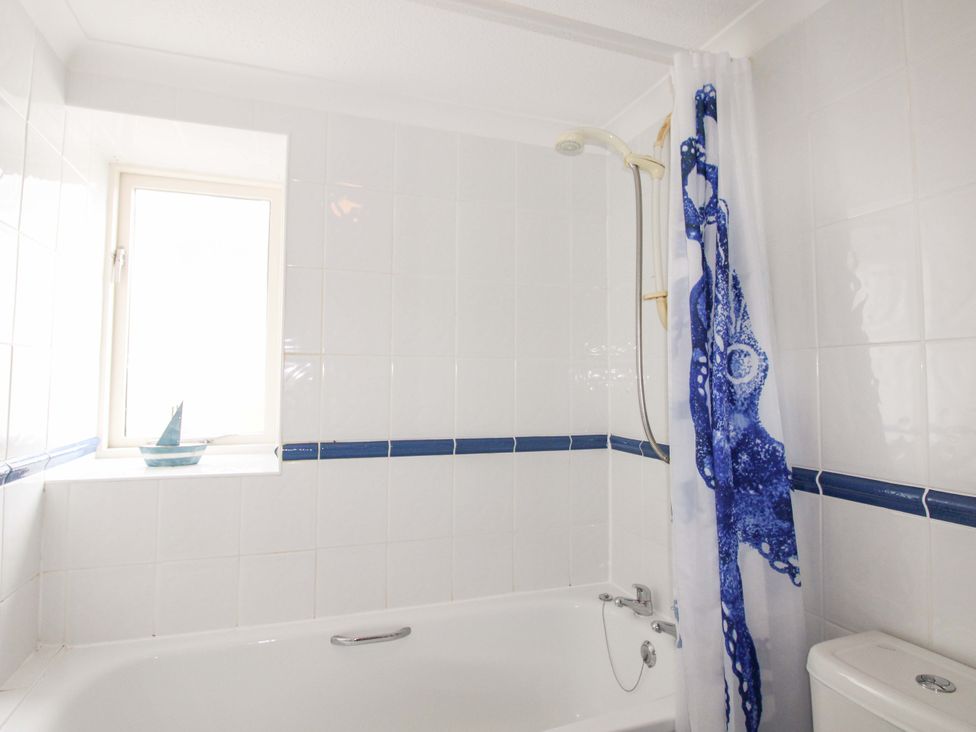 A bathroom with a bathtub and shower curtain at Orchard Barn Salcombe
