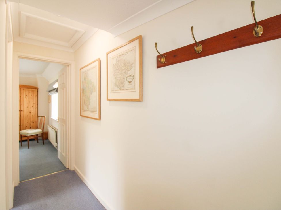A hallway with coat hooks and framed maps at Orchard Barn Salcombe