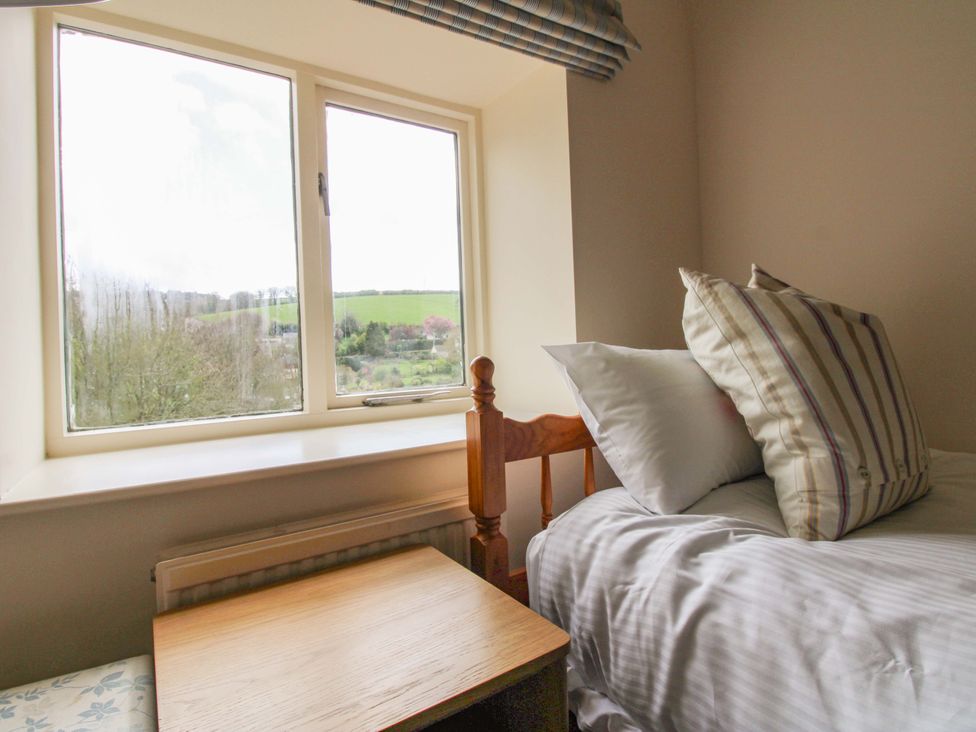 A bedroom with a bed and table next to a window at Orchard Barn Salcombe