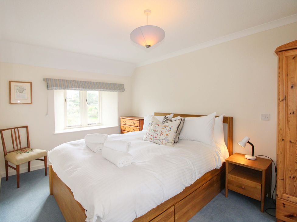 A bedroom with a wooden bed and writing desk at Orchard Barn Salcombe