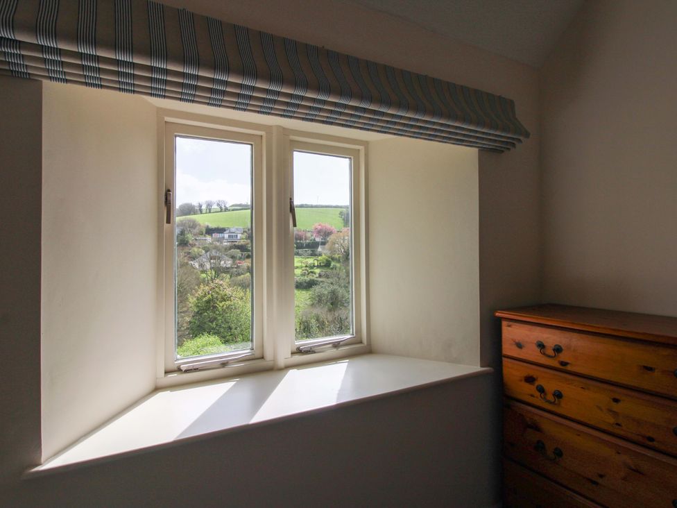 A bedroom with a window overlooking a landscape at Orchard Barn Salcombe