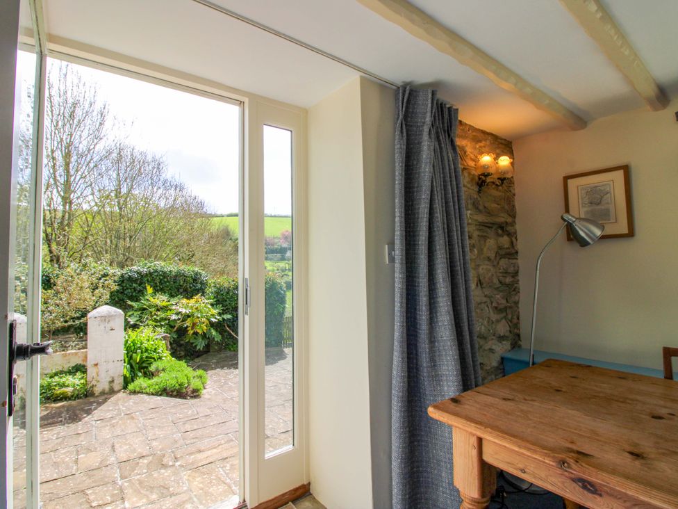A dining room with a table and a view of the garden at Orchard Barn Salcombe