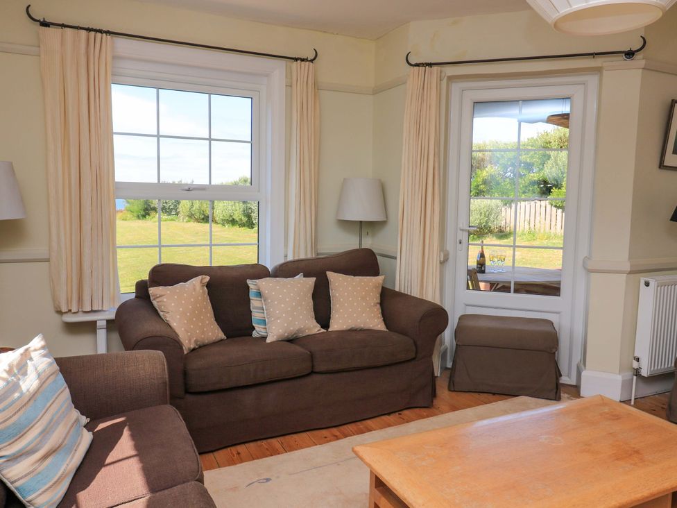 A living room with a sofa and cushions at Savernake in Thurlestone