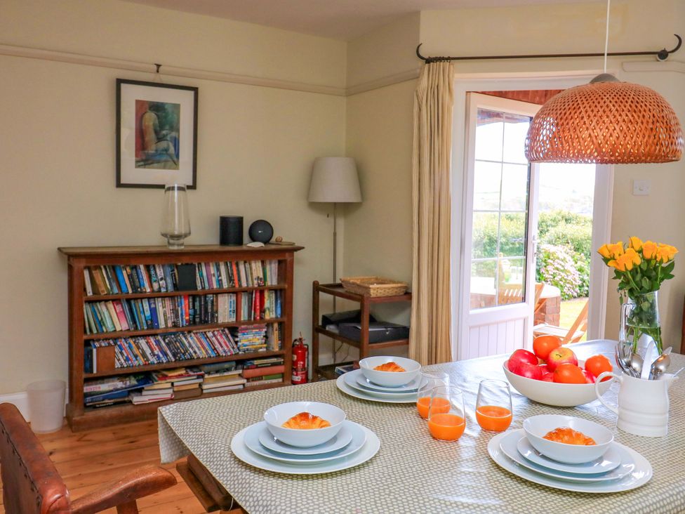 A dining room with a table set for meals at Savernake in Thurlestone