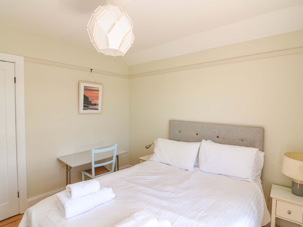 A bedroom with a bed and desk at Savernake in Thurlestone