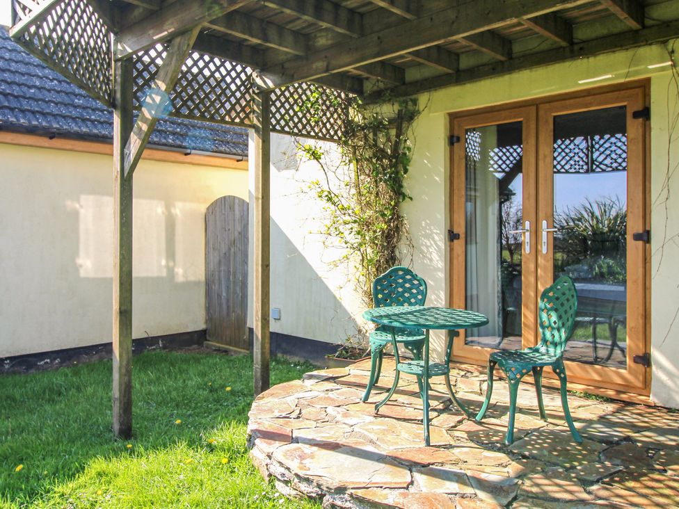 A table and chairs under a wooden structure in an outdoor area at The Station in Bolberry