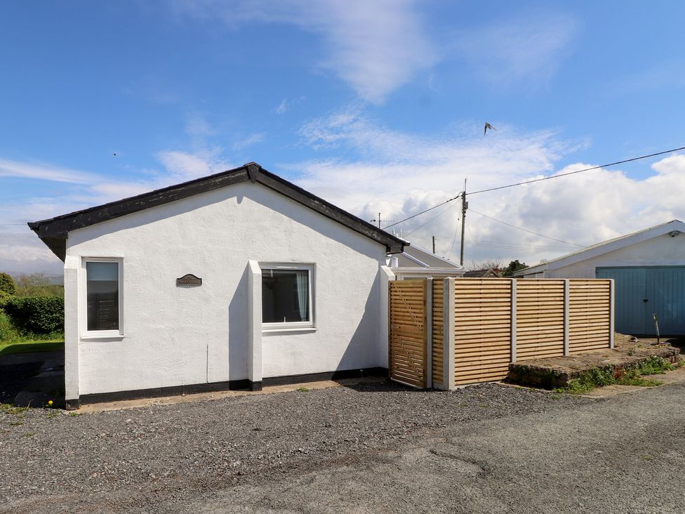 A house with a wooden fence and gravel pathway at Maes Y Coed in Morfa Nefyn
