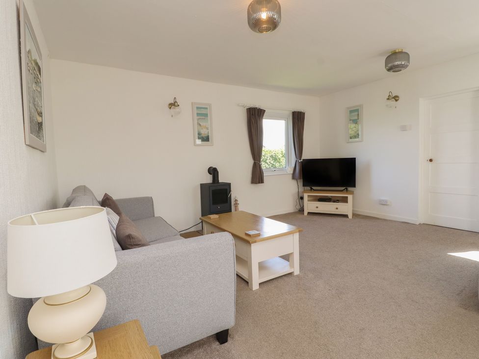 A living room with a sofa, coffee table, and television at Maes Y Coed in Morfa Nefyn