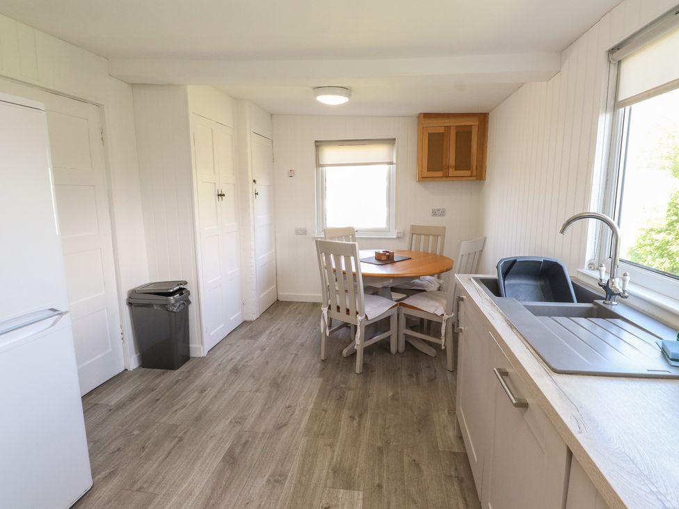 A kitchen with a table and chairs at Maes Y Coed in Morfa Nefyn