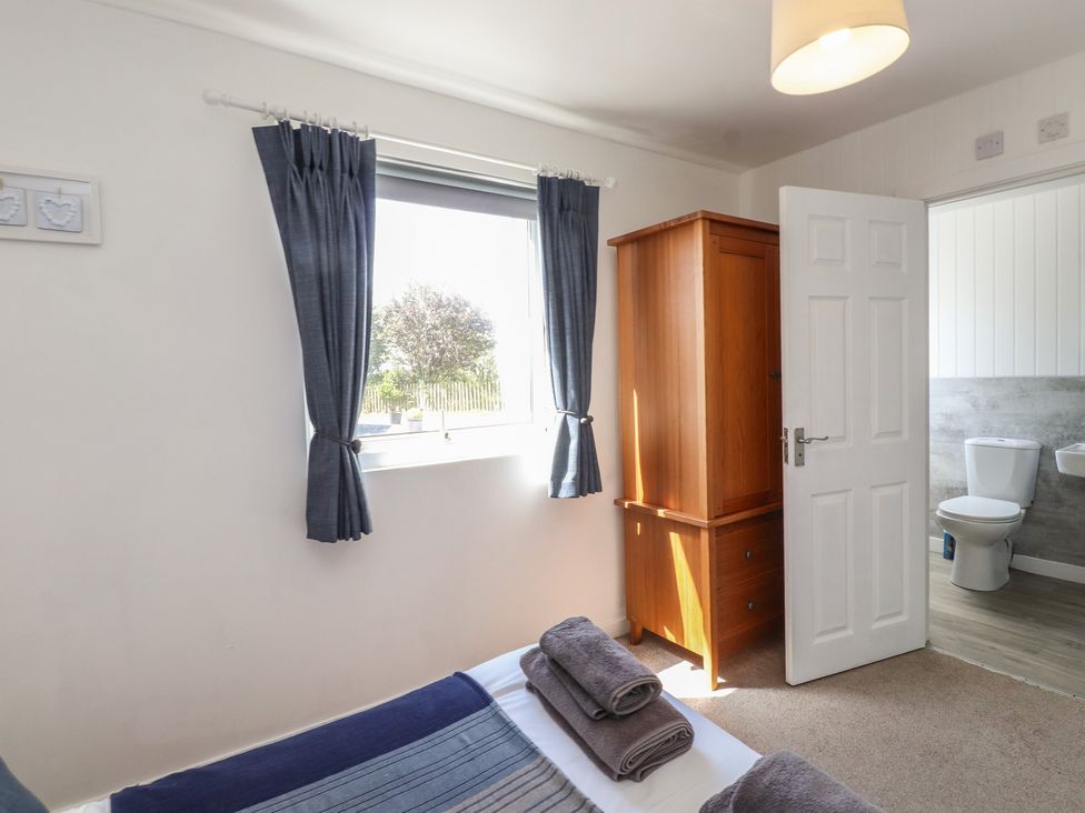 A bedroom with a wardrobe and window at Maes Y Coed in Morfa Nefyn