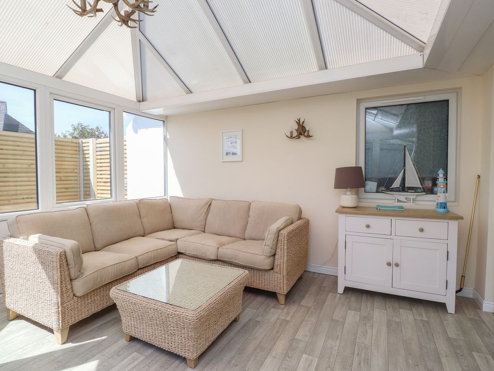 A conservatory with a sofa and coffee table at Maes Y Coed in Morfa Nefyn