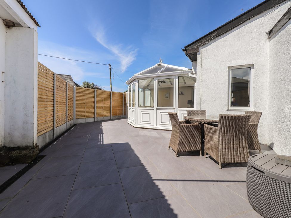 A garden with a conservatory and outdoor furniture at Maes Y Coed in Morfa Nefyn