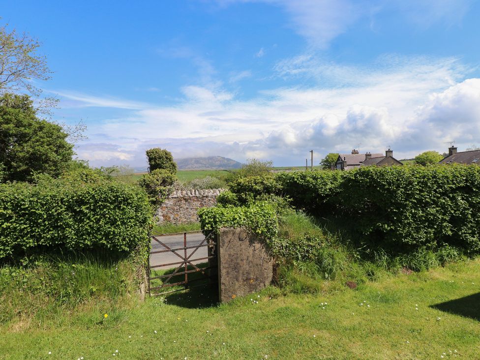 A view of a gate leading to a road among greenery at Maes Y Coed Morfa Nefyn