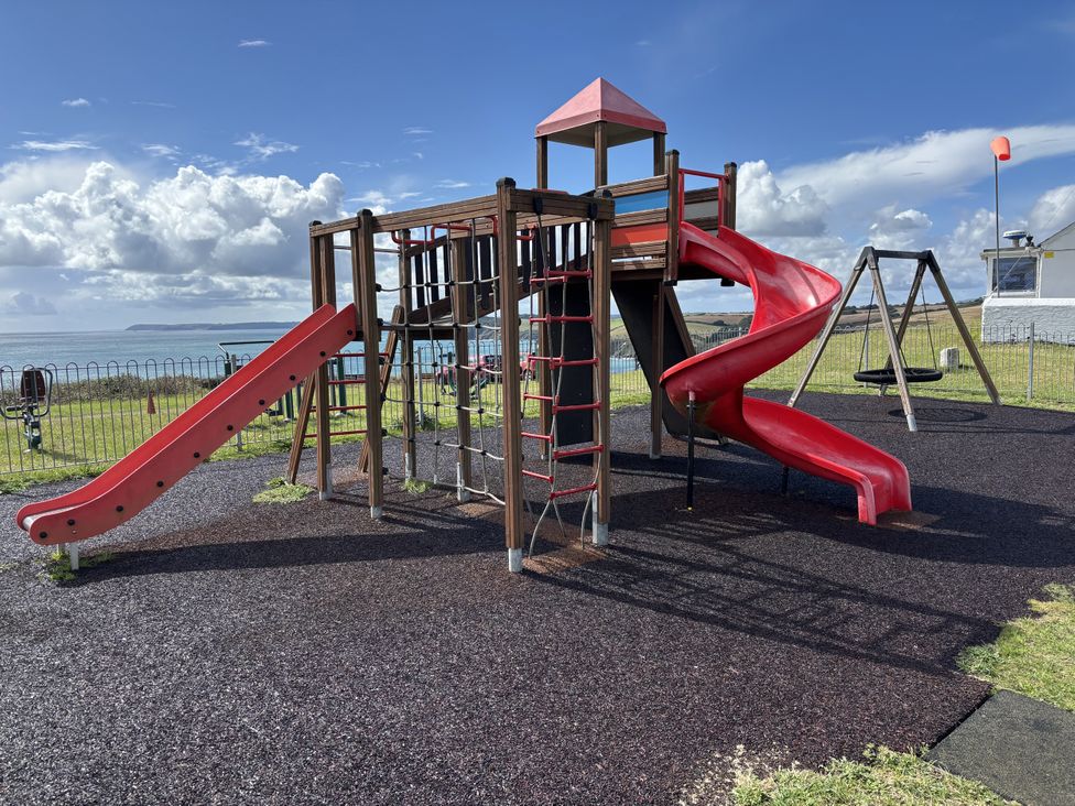A playground with slides and swings by the sea at Postcard Lodge in Polruan