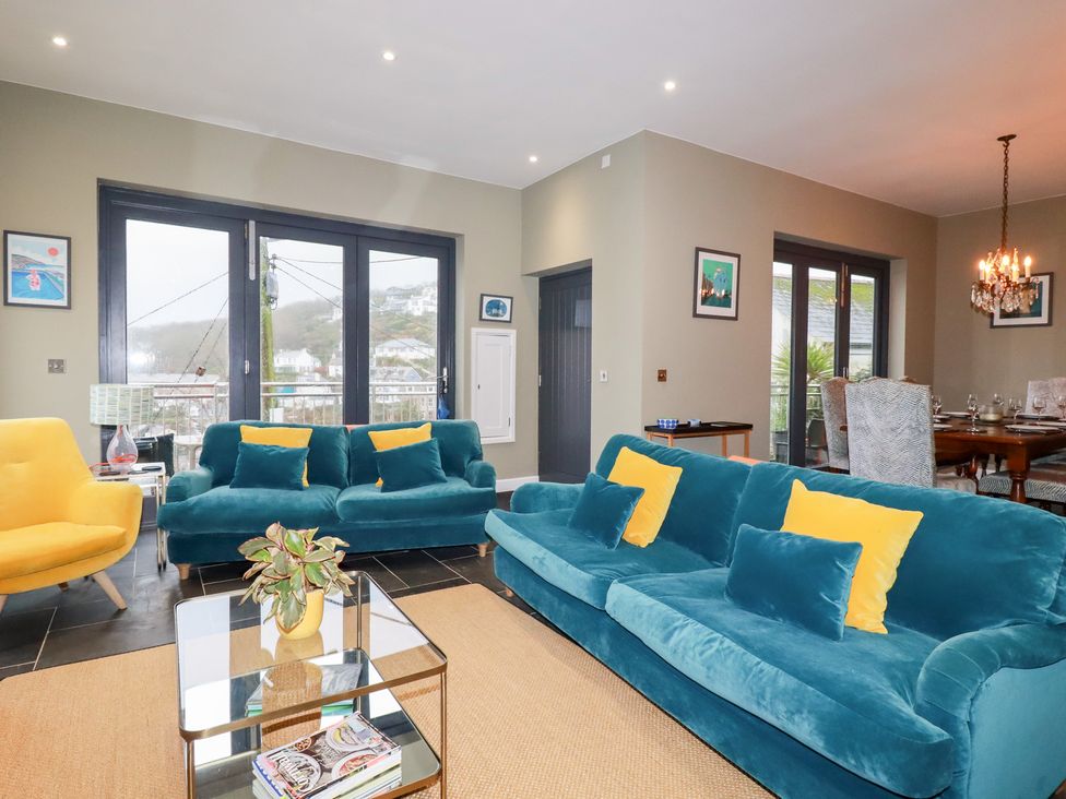 A living room with teal sofa and armchairs at Postcard Lodge in Polruan