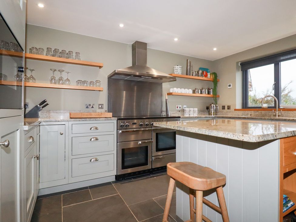 A kitchen with appliances and glasses on shelves at Postcard Lodge Polruan