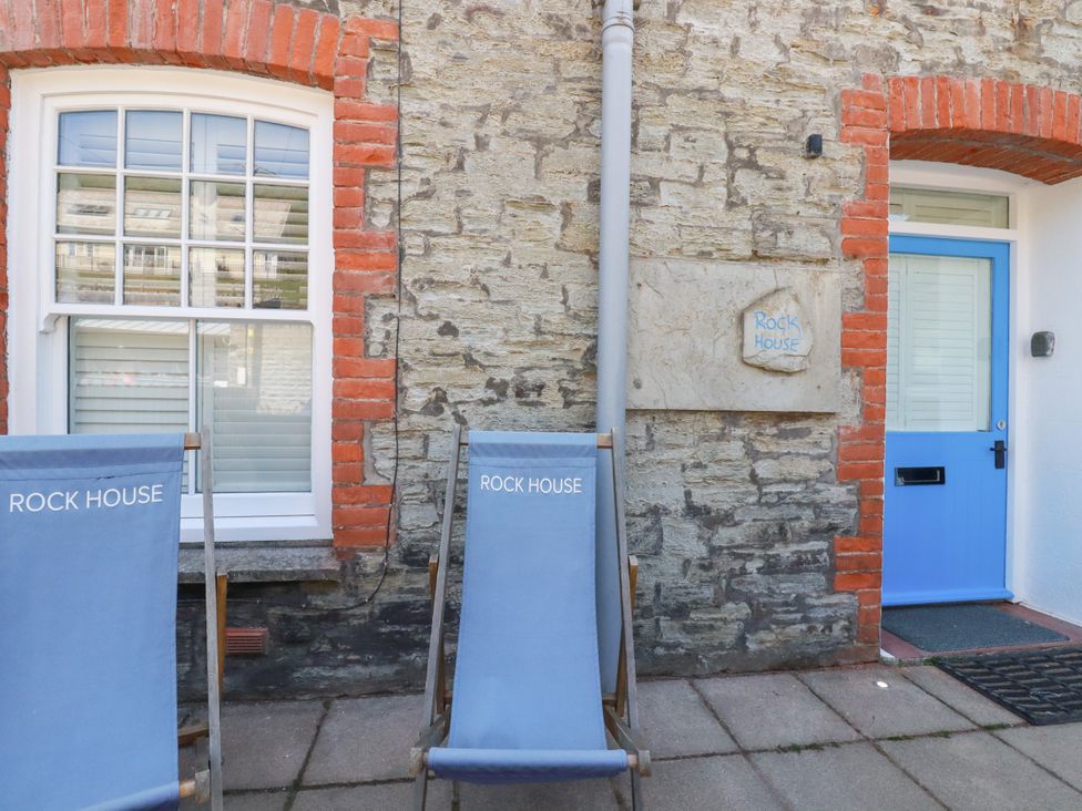 An outdoor area with deck chairs and a blue door at Rock House in Trebarwith Strand near Tintagel