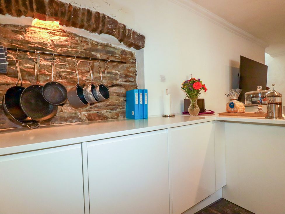A kitchen with hanging pots and a television at Rock House Trebarwith Strand near Tintagel