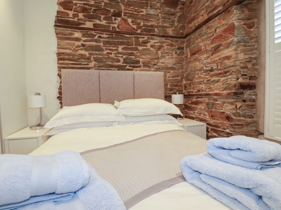 A bedroom with a bed and towels at Rock House Trebarwith Strand near Tintagel