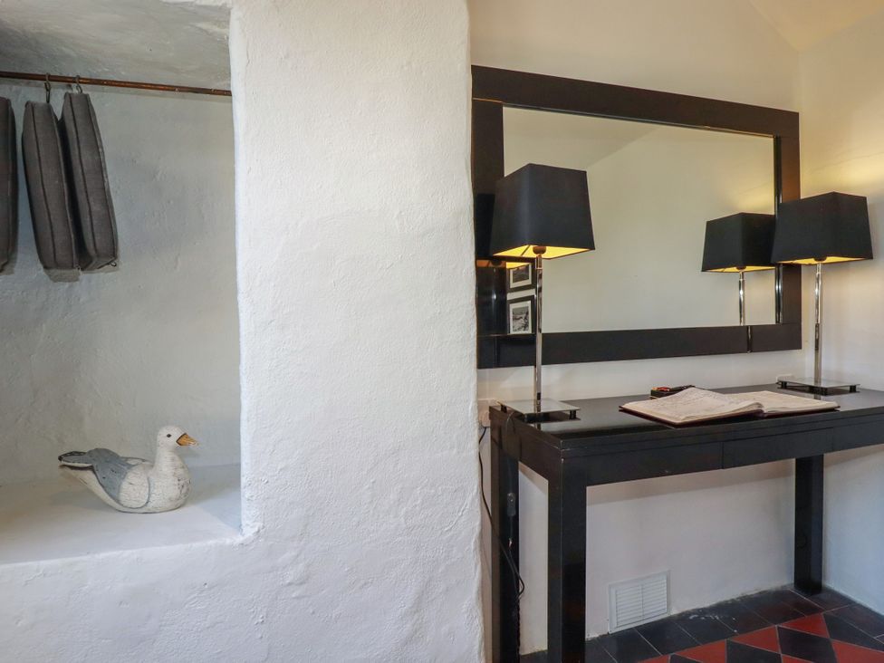 An entrance hall with a table and mirror at Rock House in Trebarwith Strand near Tintagel