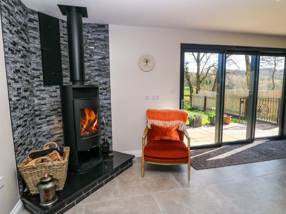 A living room with a wood stove and a chair at The Old Dairy Cotleigh near Honiton