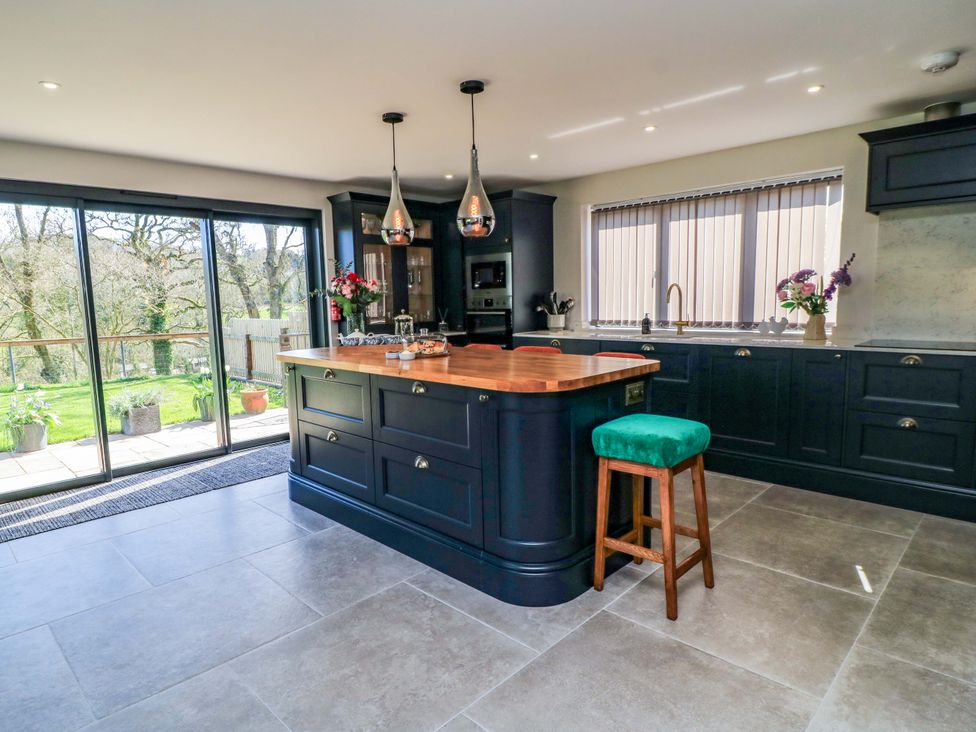 A kitchen with an island and stools at The Old Dairy Cotleigh near Honiton