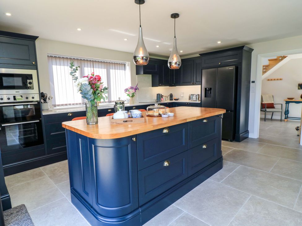A kitchen with an island, sink, refrigerator, and oven at The Old Dairy Cotleigh near Honiton