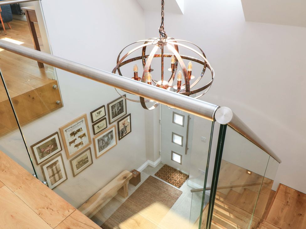 A staircase with a chandelier and wall art at The Old Dairy Cotleigh near Honiton