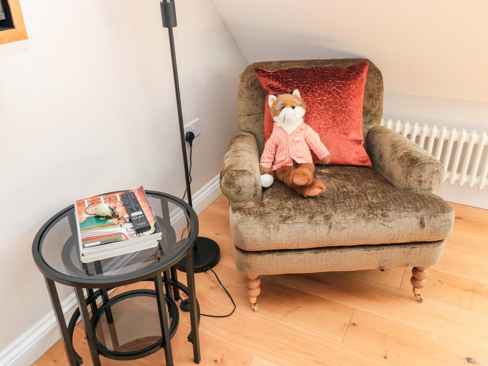 A sitting room with an armchair and a side table at The Old Dairy Cotleigh near Honiton