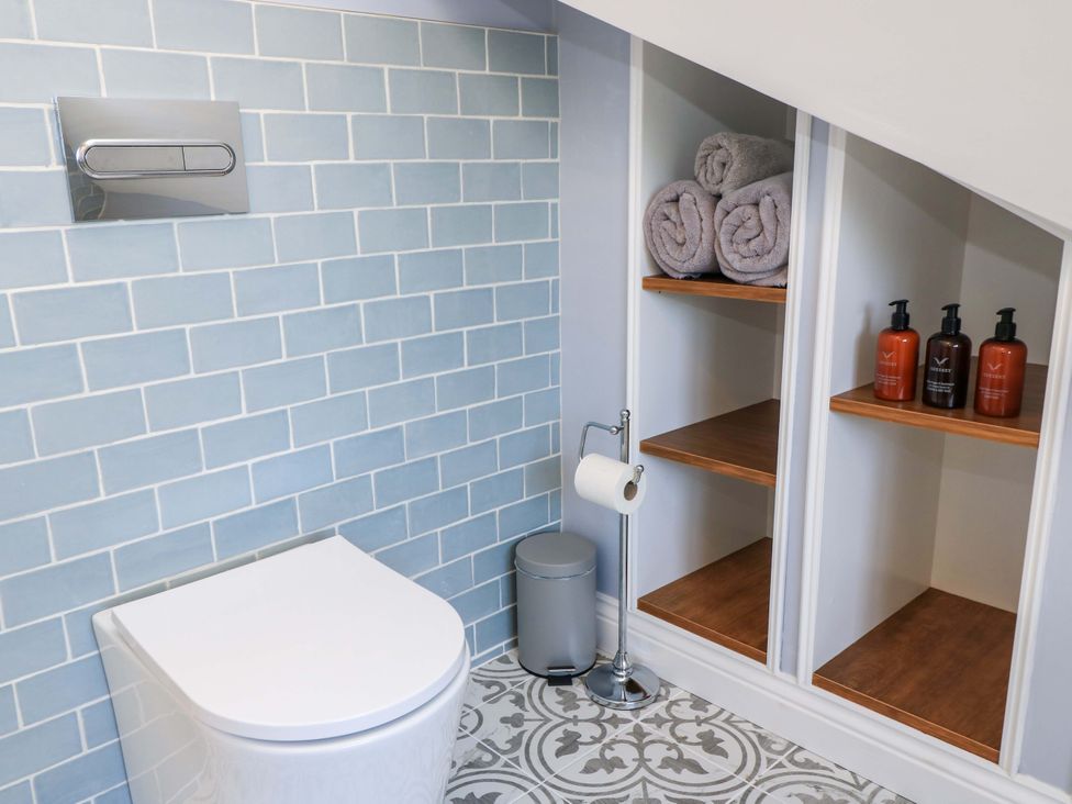 A bathroom with a toilet and shelving at The Old Dairy Cotleigh near Honiton