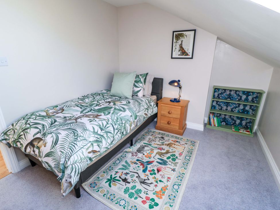 A bedroom with a bed and bookshelf at The Old Dairy in Cotleigh near Honiton