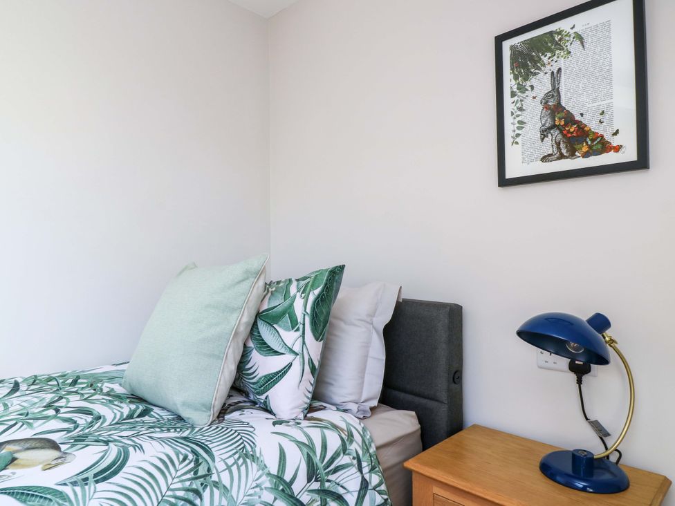 A bedroom with a bed, pillows, a bedside table and a lamp at The Old Dairy Cotleigh near Honiton