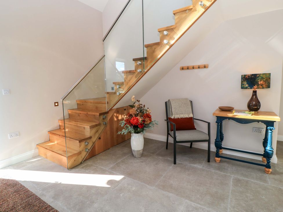 A hallway with stairs and a chair at The Old Dairy in Cotleigh near Honiton
