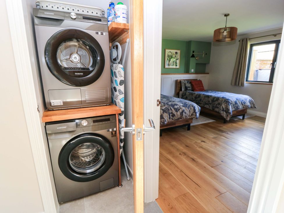 A washing machine and dryer with two beds in a bedroom at The Old Dairy Cotleigh near Honiton