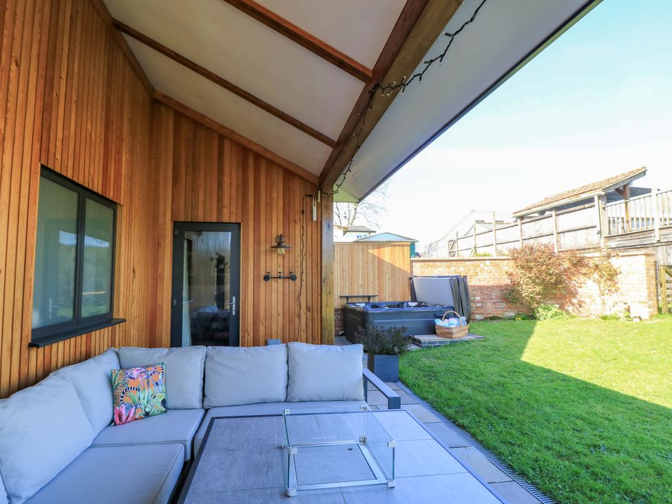 A seating area with a couch and table next to a hot tub at The Old Dairy Cotleigh near Honiton