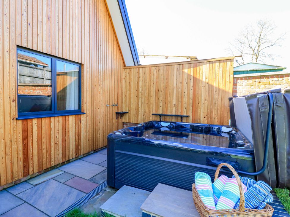An outdoor area with a hot tub and wooden walls at The Old Dairy Cotleigh near Honiton