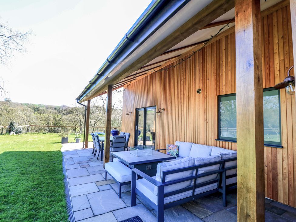An outdoor patio with seating and a table at The Old Dairy in Cotleigh near Honiton