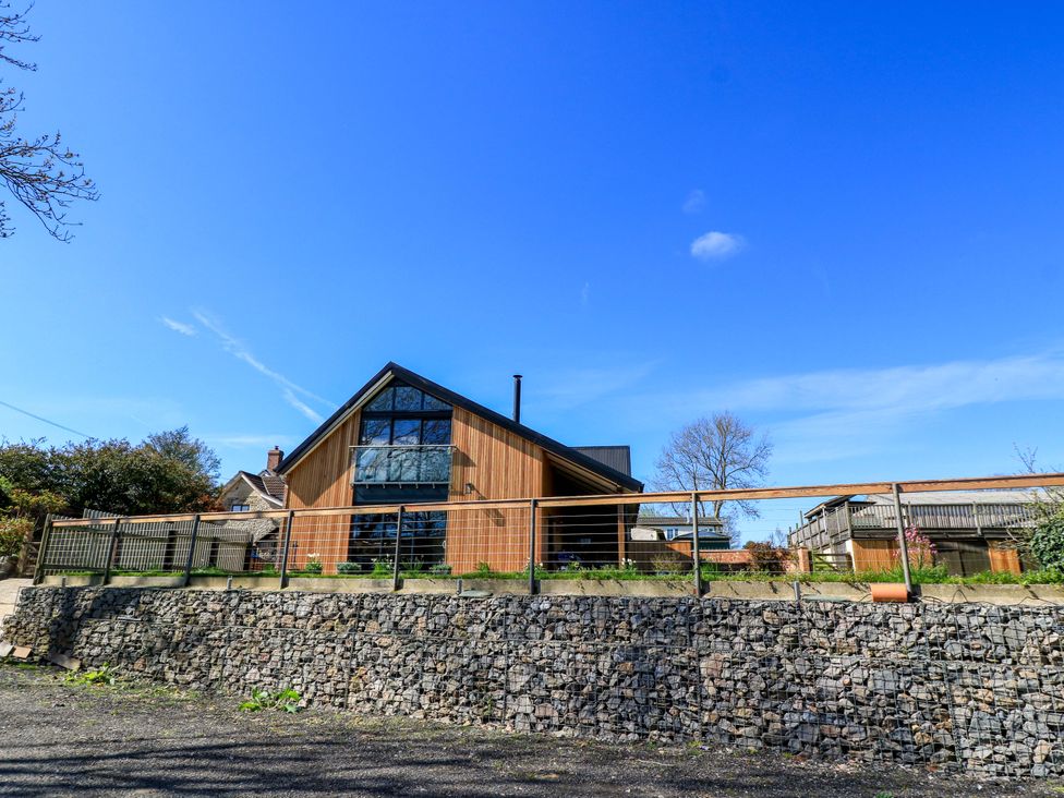 A house with wooden exterior and a garden at The Old Dairy in Cotleigh near Honiton