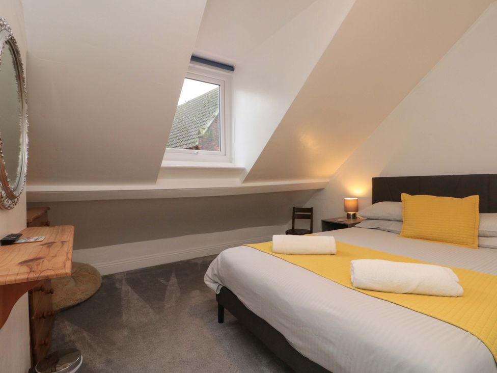 A bedroom with a bed and a mirror at Saints Cottage Scarborough